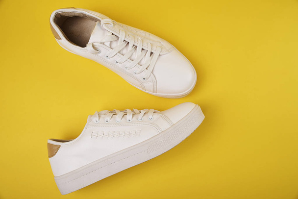 White stylish sneakers on yellow background - Foto, afbeelding