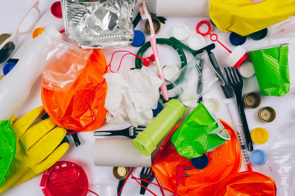Plastic pollution concept. Be plastic free. Broken single-use colorful plates, forks, cups, bottle, straw, toothbrush, lids, foil and other plastic trash on white background. New rules to reduce - Φωτογραφία, εικόνα