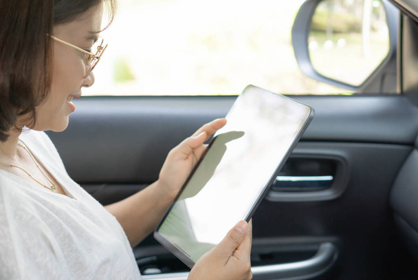 Крупним планом азіатська жінка використовує цифровий планшет в машині з щасливим обличчям
 - Фото, зображення