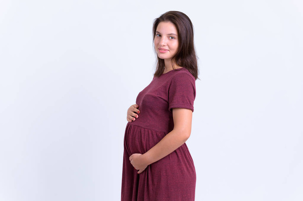 Widok profilu młodej pięknej kobiety w ciąży patrząc na kamerę - Zdjęcie, obraz