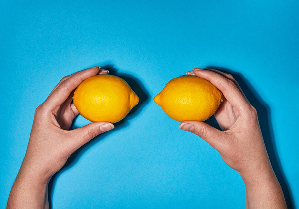 Lemon in hand on blue background. Flat lay, top view, copy space . Food concept. - Photo, Image
