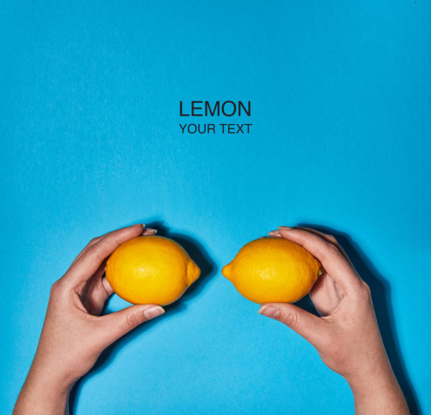 青の背景に手にレモンで作られた創造的なレイアウト。フラットレイ、トップビュー、コピースペース。食品コンセプト. - 写真・画像