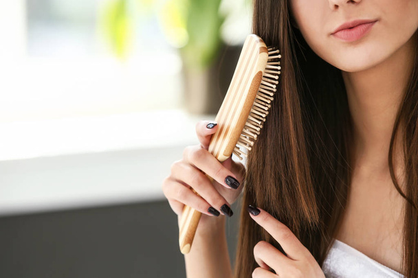 Kaunis nuori nainen harjaamalla hänen terveet pitkät hiukset kylpyhuoneessa
 - Valokuva, kuva