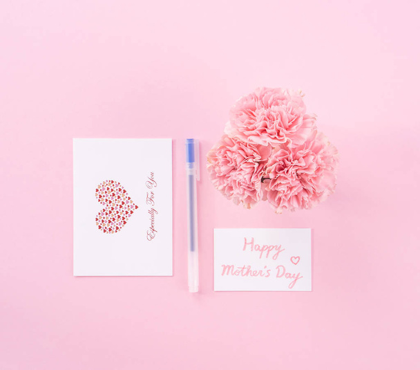 Top view, flat lay, mock up, copy space, handwritten greeting card template isolated with pale pink background, idea concept of thanks, wishes, craft carnations bouquet - Photo, image