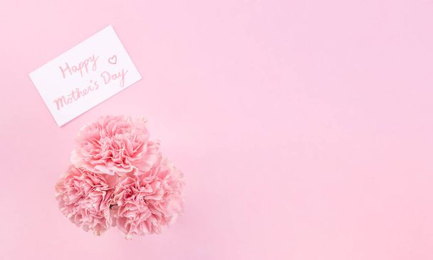 Top view, flat lay, mock up, copy space, handwritten greeting card template isolated with pale pink background, idea concept of thanks, wishes, craft carnations bouquet - Foto, imagen