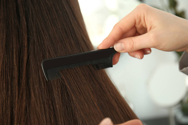 Cabeleireiro pentear cabelos longos de mulher jovem no salão
 - Foto, Imagem