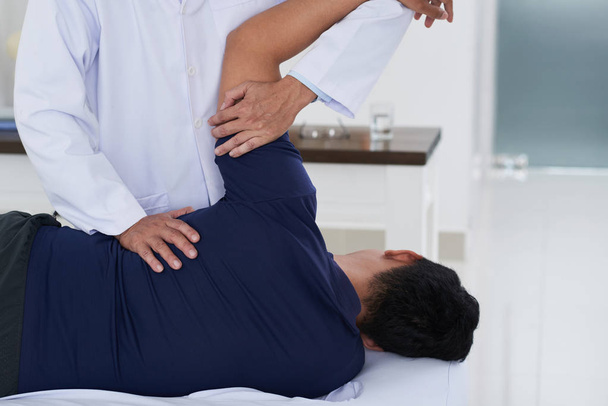 Chiropractor adjusting spine of patient with back pain - Photo, image