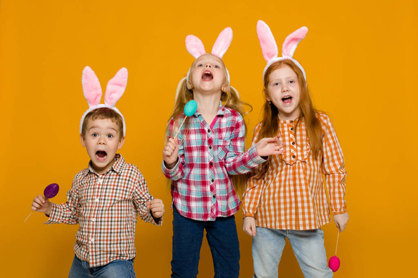 two little girls and boy with Easter bunny ears holding colorful eggs - Φωτογραφία, εικόνα