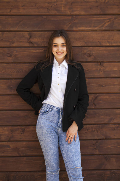 Happy teenager girl in a white shirt on a wooden wall background - Fotografie, Obrázek