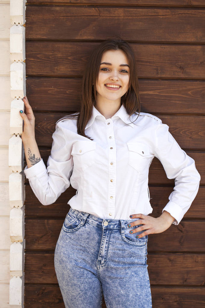 Happy teenager girl in a white shirt on a wooden wall background - Foto, imagen