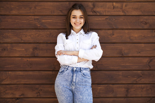 Happy teenager girl in a white shirt on a wooden wall background - Valokuva, kuva