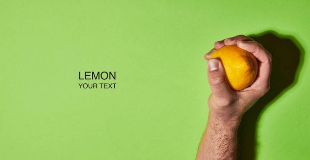 Diseño creativo hecho de limón en la mano sobre fondo verde. Piso tendido, vista superior, espacio para copiar. Concepto alimenticio
. - Foto, Imagen