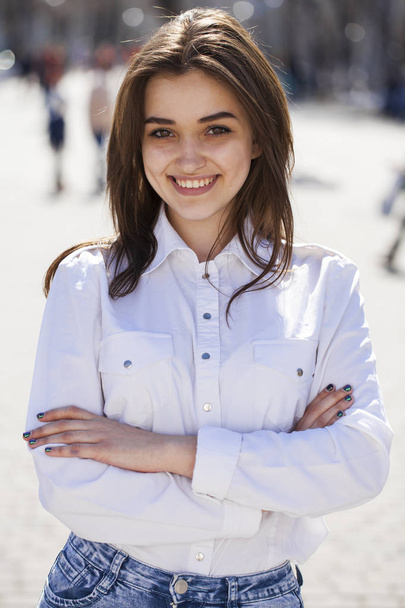 Young beautiful brunette girl in white shirt posing on spring pa - Photo, image
