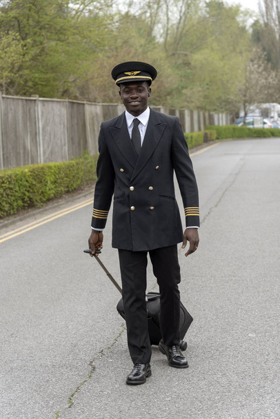 Piloto de línea aérea en uniforme caminando al trabajo tirando de una bolsa de vuelo
. - Foto, Imagen