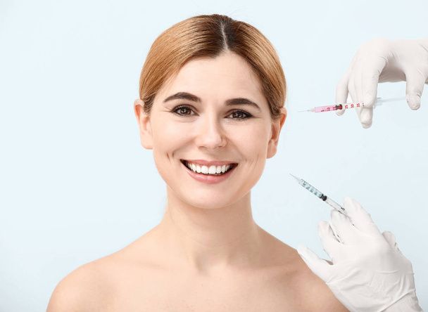 Beautiful woman and hands holding syringes for anti-aging injections on white background - Photo, Image