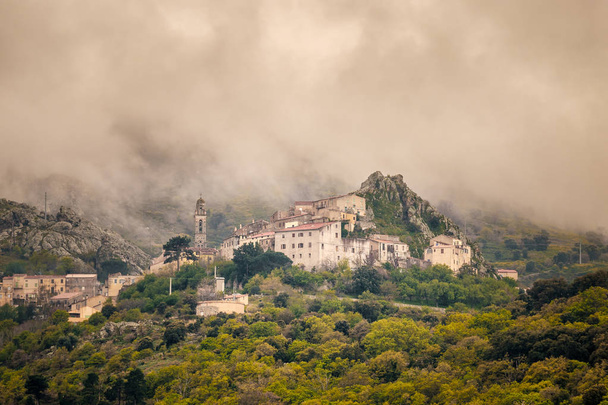 Clouds over mountain village of Speloncato in Corsica - Photo, Image