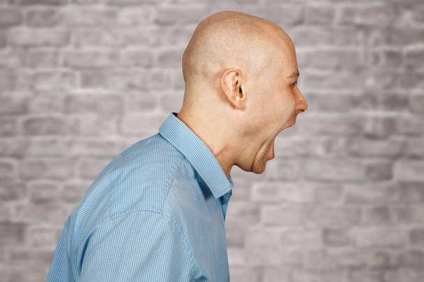 Retrato agressivo careca irritado Homem chefe, gritando subordinado na parede de tijolos fundo branco
 - Foto, Imagem