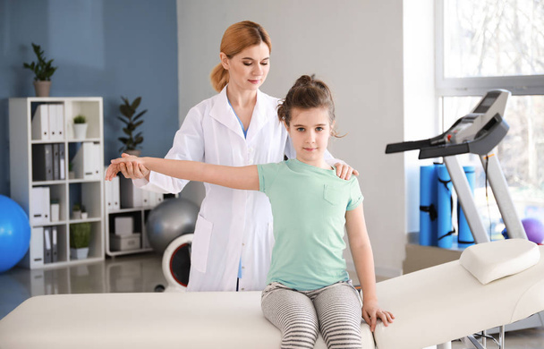 Физиотерапевт, работающий с маленькой девочкой в реабилитационном центре
 - Фото, изображение