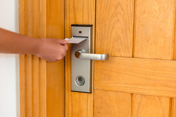 Mão feminina colocando e segurando chave magnética interruptor de cartão para abrir a porta do quarto do hotel
 - Foto, Imagem