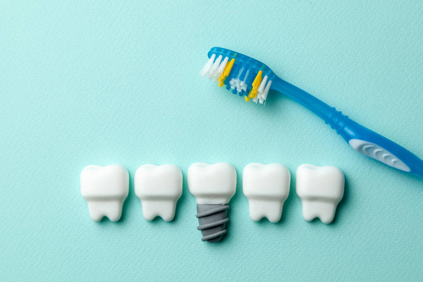 Dentes brancos saudáveis e implantes em fundo de hortelã verde com escova de dentes
 - Foto, Imagem