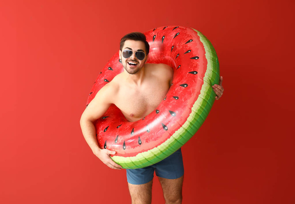 Handsome man with inflatable ring on color background - Photo, Image