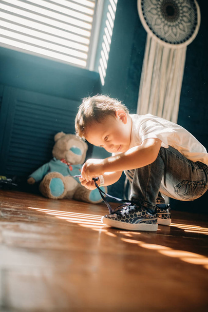 Niño aprende a atar los cordones de los zapatos en sus zapatillas
. - Foto, Imagen