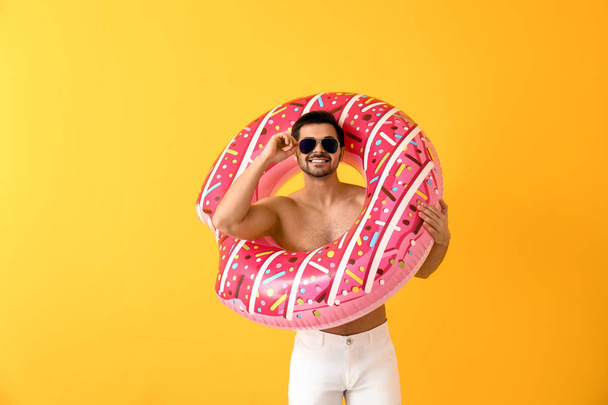 Handsome man with inflatable ring on color background - Фото, изображение