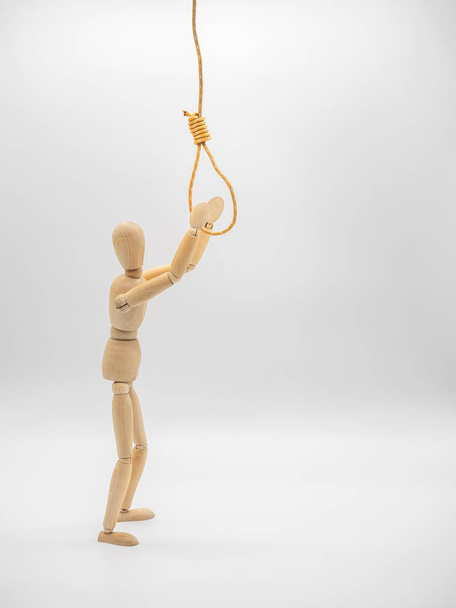Miniature wooden doll is pulling hands to hanging rope with gallow noose.  - Fotó, kép
