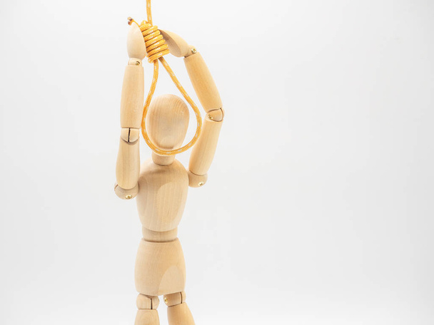 Miniature wooden doll is putting head in the noose of gallows isolated on white. Suicide concept with the hanging rope. - Photo, Image