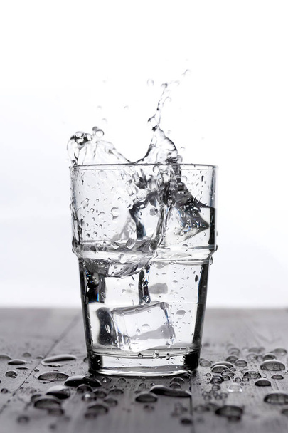 Wasserspritzer mit Eis im Glas, auf weiß - Foto, Bild