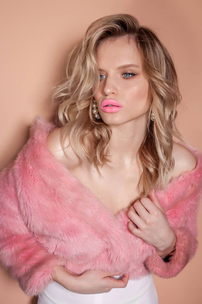 Νέος σέξι κορίτσι σε ένα ροζ παλτό, ξανθιά σε ένα γούνινο παλτό. - Φωτογραφία, εικόνα