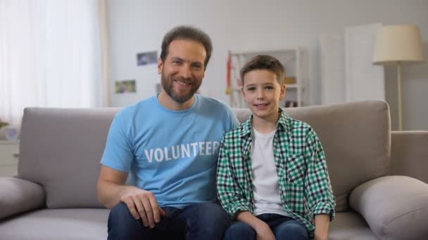 Smiling middle-aged volunteer and schoolboy shoving thumbs-up to camera, ad - Video