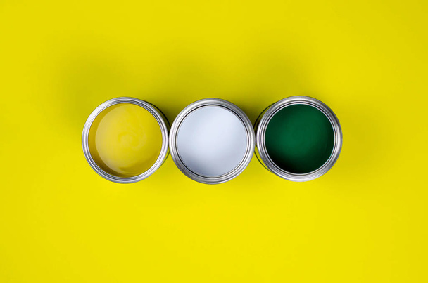 Three cans of multicolored paint on a yellow background. - Foto, immagini