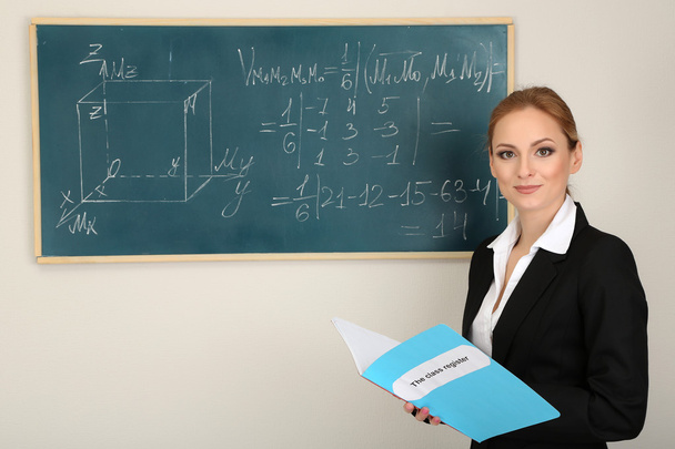 Portrait of teacher woman near the chalkboard in classroom - Fotó, kép