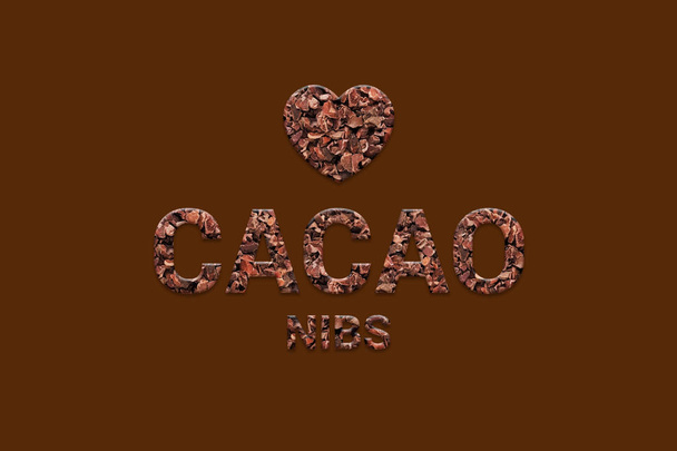 Textura de plumas de cacao con forma de corazón sobre fondo marrón oscuro. Tipografía de frijoles orgánicos crudos. Vegano, Súper comida y comida de desintoxicación
. - Foto, Imagen