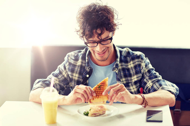happy man eating sandwich at cafe for lunch - Fotoğraf, Görsel