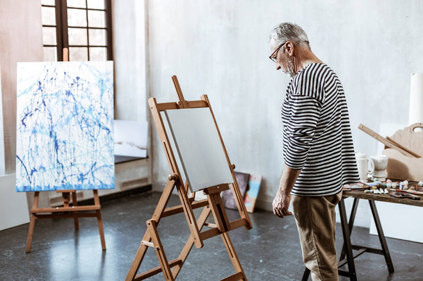 Artist standing in front of white canvas having no inspiration - Photo, Image