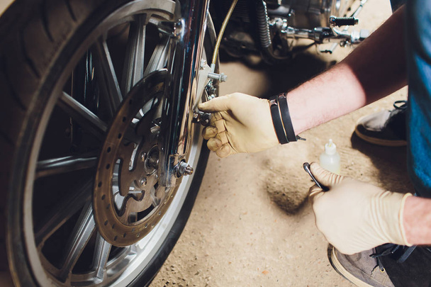 Man fixing bike. Confident young man repairing motorcycle near his garage. - Fotó, kép