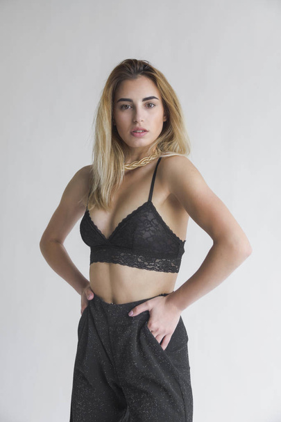 portrait of  young blond woman  posing in black bra and pants in studio - Foto, afbeelding