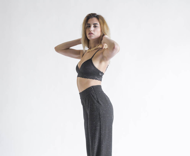 portrait of  young blond woman  posing in black bra and pants in studio - Photo, Image