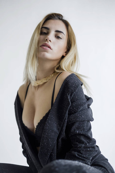 портрет молодой блондинки, позирующей в черном лифчике и брюках в студии
 - Фото, изображение