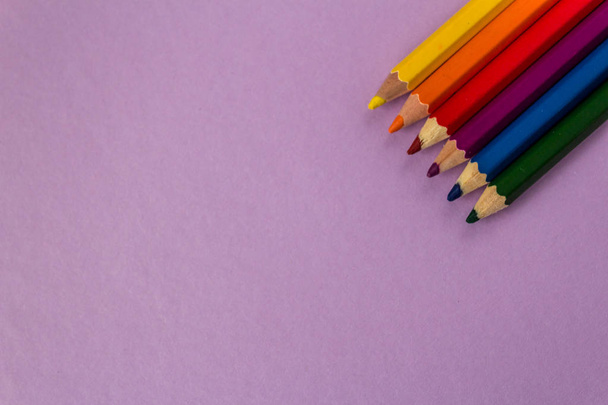 Um número de lápis coloridos em uma fileira no fundo roxo
.  - Foto, Imagem