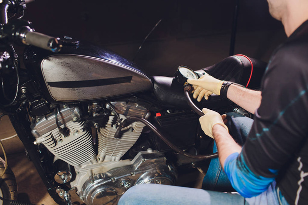 Man fixing bike. Confident young man repairing motorcycle near his garage. barometer - Zdjęcie, obraz