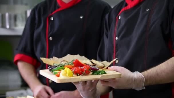 Cozinha de restaurante. Dois homens chefs terminaram de servir pratos com um gesto bellissimo
 - Filmagem, Vídeo