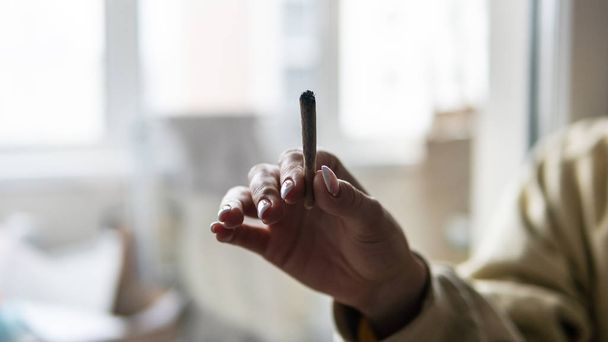 вплив марихуани на жіноче тіло. Куріння суглоба з марихуаною в жіночих руках
  - Фото, зображення