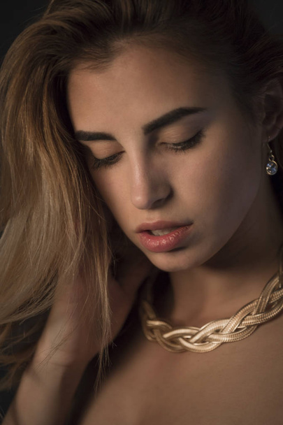portrait of  young blond woman in in jewelry  posing in studio - Photo, Image