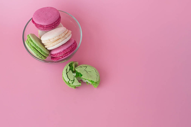 several multi-colored macarons in a glass plate on a pink backgr - Foto, imagen