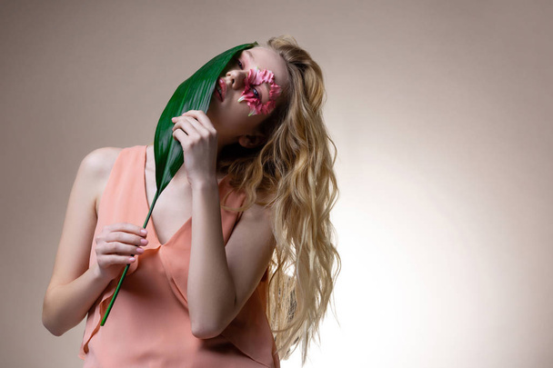 Blonde-haired model feeling good while smelling green leaf - Zdjęcie, obraz