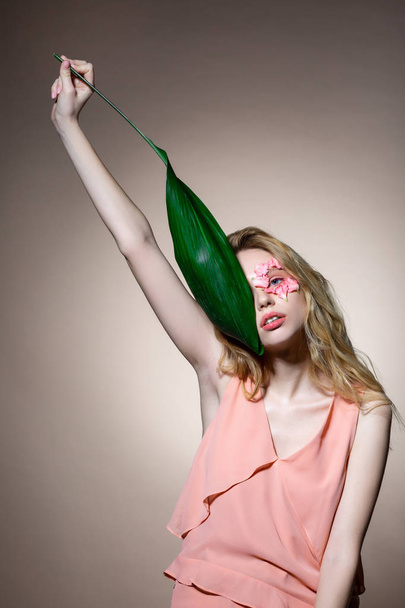 Young professional model raising hand with leaf showing poses - 写真・画像