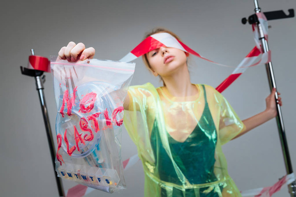 Slim model showing plastic bag with plastic items while posing - 写真・画像